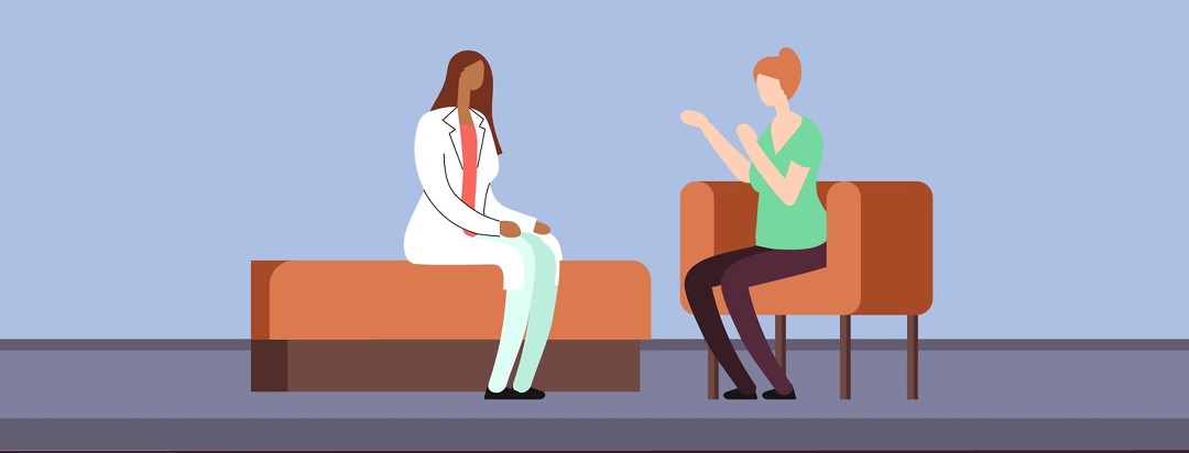A woman talks to a female doctor as they sitting together.